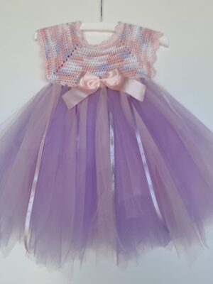 A crocheted toddler dress in soft grey-purple cotton with a pastel pink satin bow at the waist. A full tulle skirt in light purple