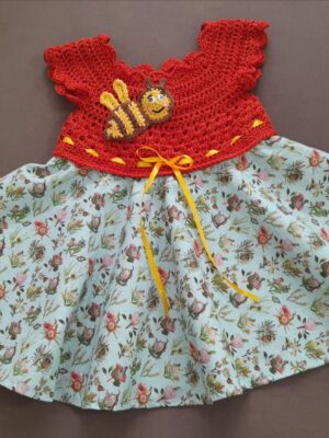 Protea Dress. The skirt of a dress featuring a red crocheted bodice embellished with a crochet bee and yellow ribbon